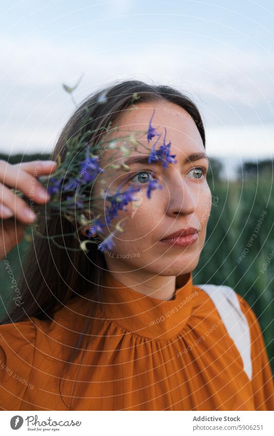 Frau in orangefarbenem Kleid hält Blumen und schaut weg Feld brünett purpur Wildblume Natur im Freien Gelassenheit Wegsehen Schönheit geblümt Beteiligung Garten