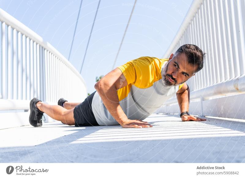 Mann macht Liegestütze auf einer sonnigen Brücke Übung Sommer Sport Inder Fitness im Freien tagsüber Gesundheit Stärke Training männlich aktiv sportlich