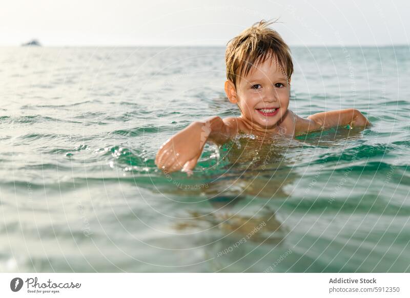 Fröhlicher Junge schwimmt bei Sonnenuntergang im Meer schwimmen MEER Strand Lächeln Wasser Italienisch Freude Feiertag Urlaub Freizeit im Freien Sommer reisen