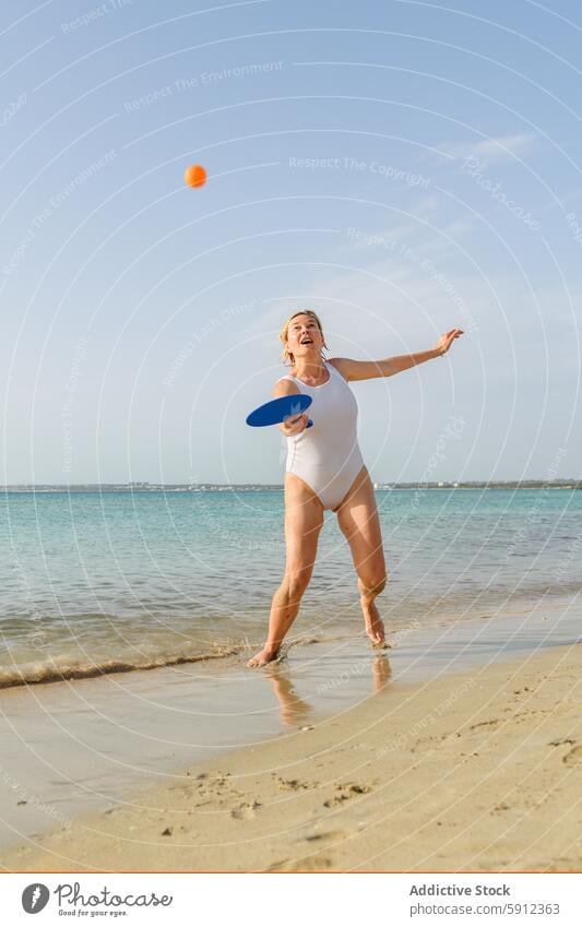 Frau spielt Paddle-Ball an einem sonnigen Strand Mutter spielen Italien Italienisch Seeküste Sand Sommer Urlaub Spaß Feiertag Familie Badebekleidung spielerisch