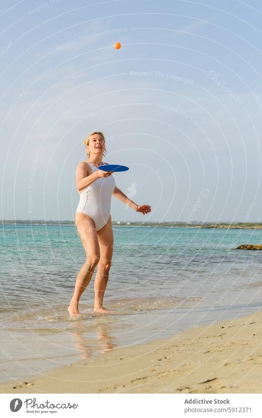 Frau spielt mit Paddel am Strand Italienisch Sand MEER Himmel sonnig Freude spielen Badeanzug weiß blau werfen Ball orange übersichtlich Wasser Feiertag Sommer