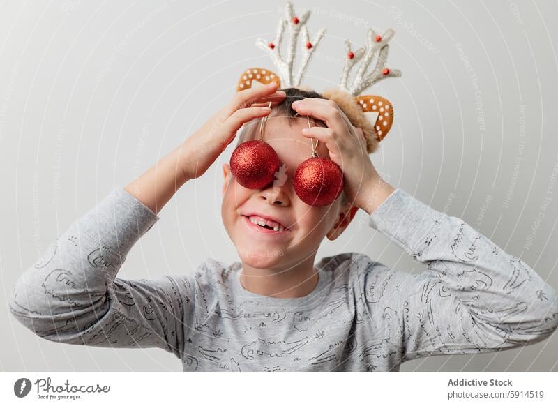 Kleiner Junge spielt mit Weihnachtsschmuck Weihnachten Ornament rot spielerisch festlich Feiertag Kind Brille Hintergrund jauchzen Freude Spaß