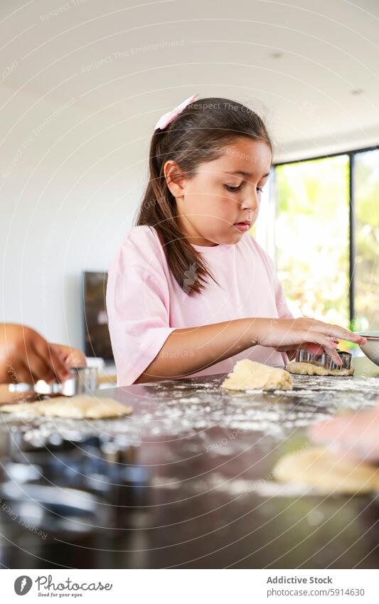 Junges Mädchen backt sorgfältig Kekse in einer sonnigen Küche backen Teigwaren Kutter Fokus rosa Hemd modern hell aufmerksam freudig Familie Backtag Kind Koch