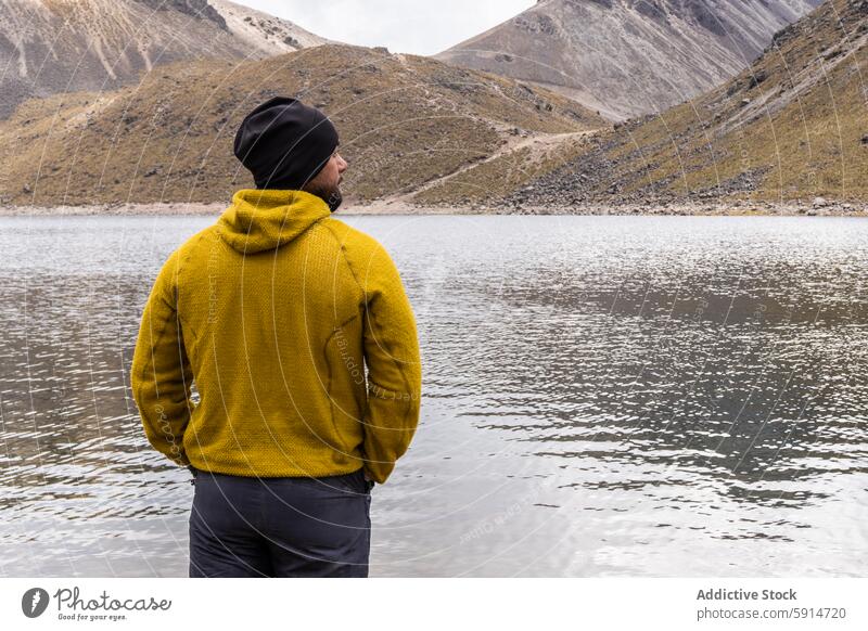 Rückenansicht eines unkenntlichen Mannes in gelber Jacke am Bergsee Rückansicht anonym gesichtslos Berge u. Gebirge See im Freien Natur Landschaft Wasser