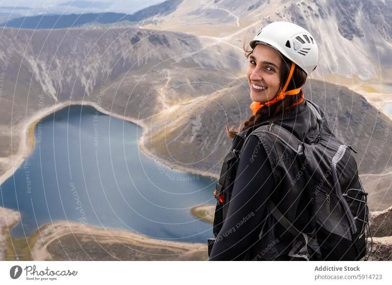 Lächelnde Wanderin mit Helm und Blick auf einen erloschenen Vulkan Frau Wanderer Schutzhelm ruhend See Berge u. Gebirge Abenteuer im Freien Natur Sport