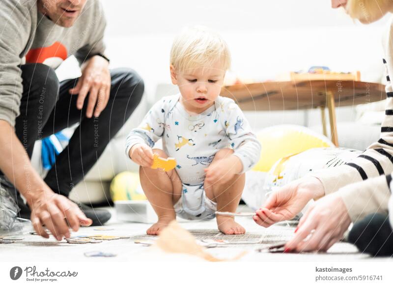 Eltern spielen Spiele mit Kind. Kleines Kleinkind beim Puzzeln. Infant Baby Junge lernt, Probleme zu lösen und entwickelt kognitive Fähigkeiten. Kind Entwicklung Konzept