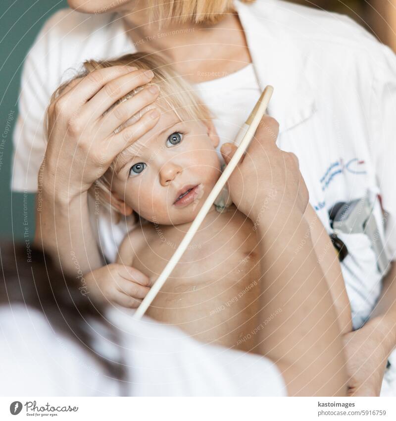 Kleinkind, das von einem Kardiologen im Rahmen der regelmäßigen ärztlichen Untersuchung beim Kinderarzt mit einer Ultraschalluntersuchung auf Herzgeräusche untersucht wird.