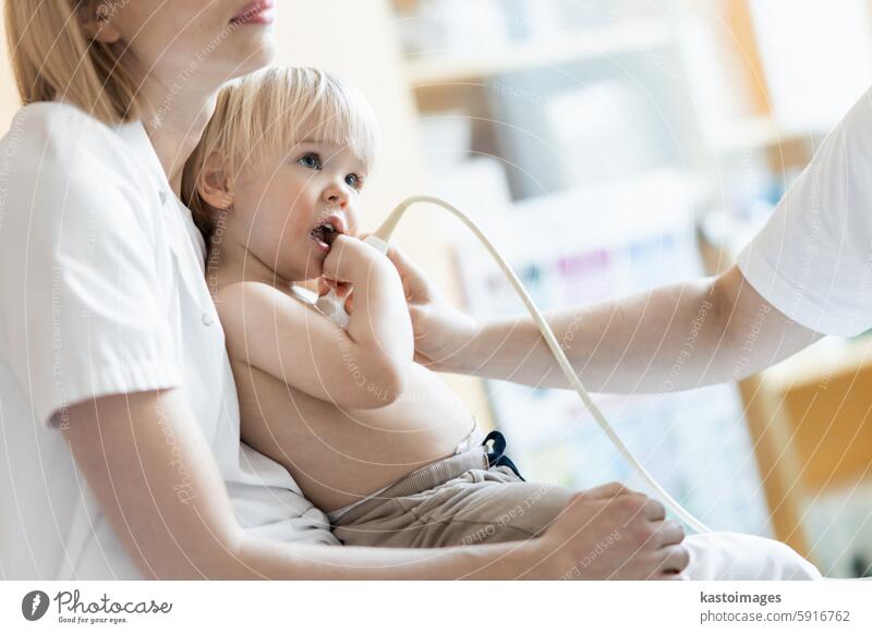 Kleinkind, das von einem Kardiologen im Rahmen der regelmäßigen ärztlichen Untersuchung beim Kinderarzt mit einer Ultraschalluntersuchung auf Herzgeräusche untersucht wird.