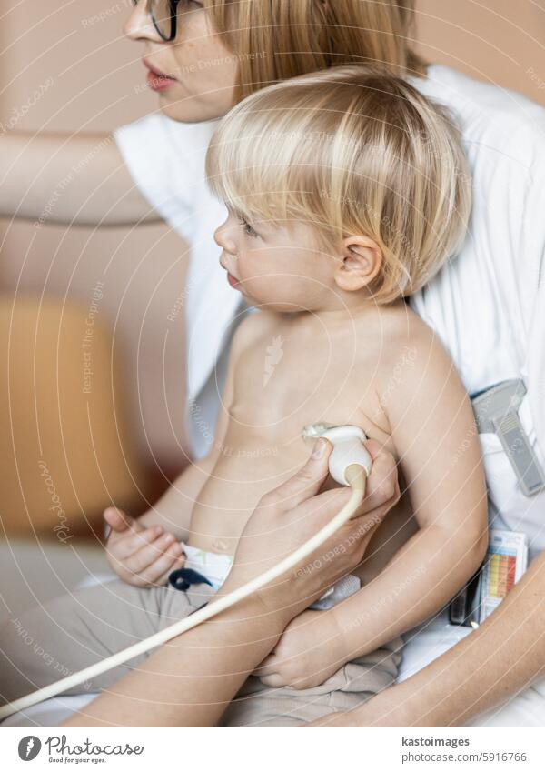 Kleinkind, das von einem Kardiologen im Rahmen der regelmäßigen ärztlichen Untersuchung beim Kinderarzt mit einer Ultraschalluntersuchung auf Herzgeräusche untersucht wird.