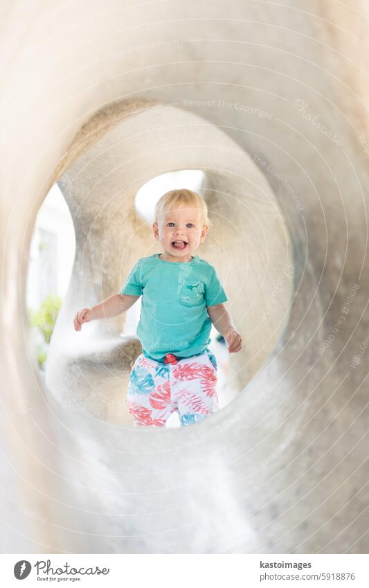 Kind spielt auf Spielplatz im Freien. Kleinkind spielt auf Schule oder Kindergarten Hof. Aktives Kind auf Stein gemeißelter Rutsche. Gesunde Sommeraktivität für Kinder. Kleiner Junge klettert im Freien.