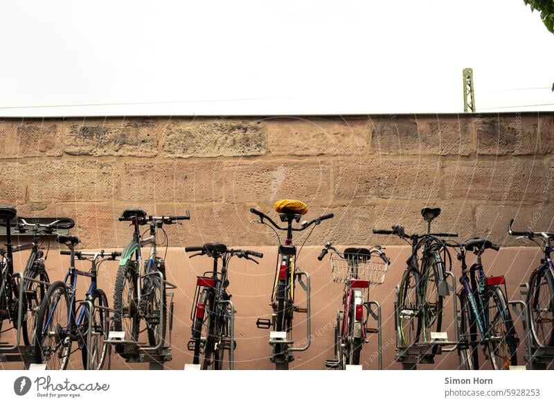 Fahrräder in einem Gestell vor einer Mauer Fahrradparkplatz Mobilität Verkehrswende parken park and ride Verkehrsmittel umweltfreundlich Fahrradständer