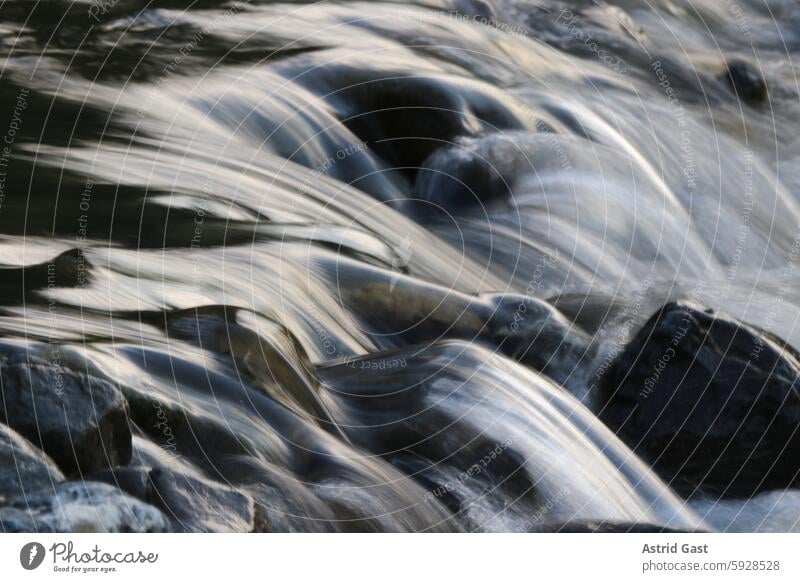 Langzeitbelichtung von einem rauschenden Bach im Abendlicht wasser bach fluss fließen fließend fließendes gewässer nah nahaufnahme langzeitbelichtung abend