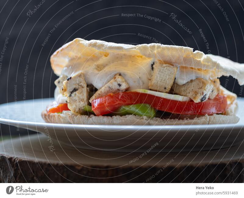 Vegetarisches Gemüse- und Tofu-Sandwich mit Joghurtsauce. schwarzer Hintergrund Snack Vegetarier Tomate Paprika Salatgurke Pita-Brot Holz weiß Tageslicht Kebab