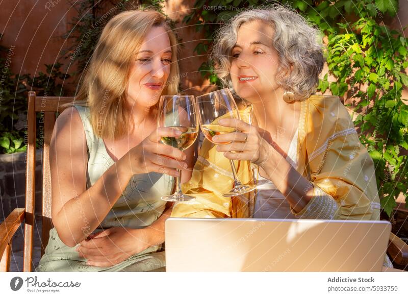 Ältere Frauen und Frauen mittleren Alters genießen den Wein im Freien älter Weißwein Gespräch Garten sonnig Laptop Freizeit sprechend Getränk trinken