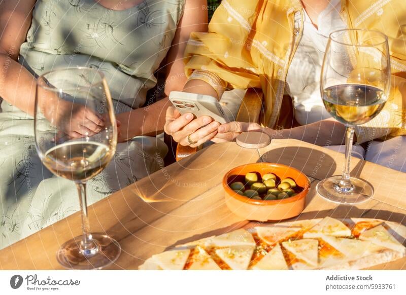 Zwei Frauen, die einen gemütlichen Nachmittag mit Wein im Freien verbringen reif Senior Freundschaft Freizeit trinken Garten Tisch Glas Sommer Smartphone