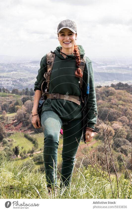 Junge Frau beim Wandern vor dem Hintergrund eines malerischen Tals wandern Natur im Freien Rucksack Lächeln Landschaft Abenteuer reisen Freizeit Aktivität grün