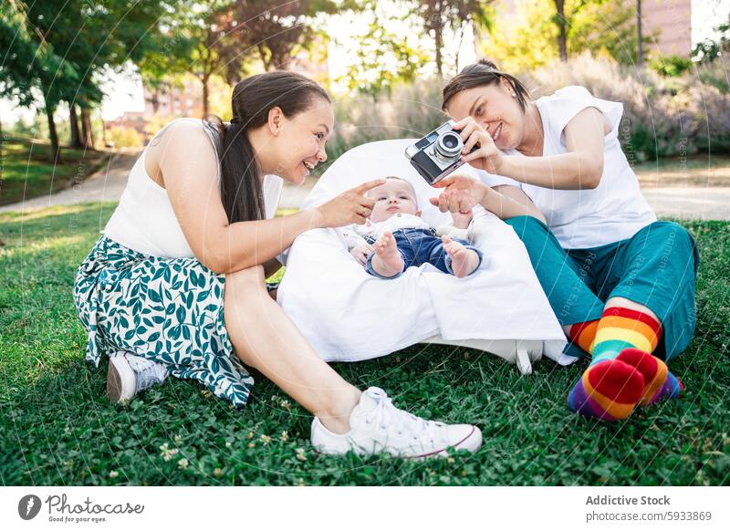 Mütter fotografieren ihr Baby bei einer spielerischen Outdoor-Session kolumbianisch Paar lgbt lesbisch Foto Park im Freien sonnig Fotografie Familie freudig