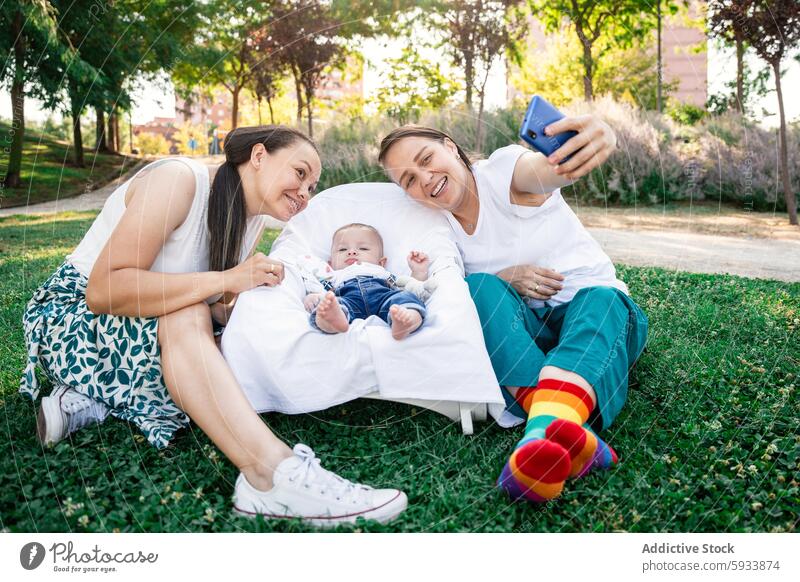 Lesbisches Paar macht ein Selfie mit ihrem Sohn und genießt die Zeit im Freien Familie lesbisch Telefon Smartphone Gras Liebe Partnerschaft Baby Säugling Freude