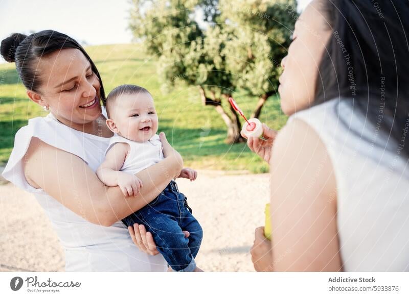 Ein lesbisches Paar genießt einen sonnigen Tag mit seinem Sohn Frau Familie Park Säugling Freude Fröhlichkeit Lächeln Mutter Schaumblase im Freien