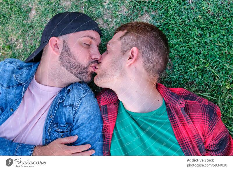 Homosexuelles Paar küssen zärtlich auf einem grasbewachsenen Hintergrund schwul Kuss Liebe Zuneigung itim Gras grün im Freien romantisch Zärtlichkeit Akzeptanz