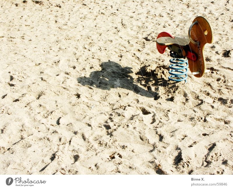 Vorsaison Spielplatz Strand Pferd Spielzeug Schaukel Wippe leer Einsamkeit Nebensaison Saison Spielen Holz Metallfeder Sand Schatten