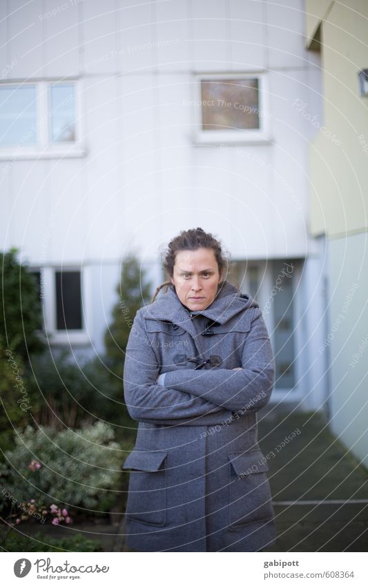 Junge Frau steht mit verschränkten Armen vor einem Wohnblock Mensch feminin Jugendliche Erwachsene Leben 1 Haus Hochhaus Gebäude Fassade rebellisch trist Stadt