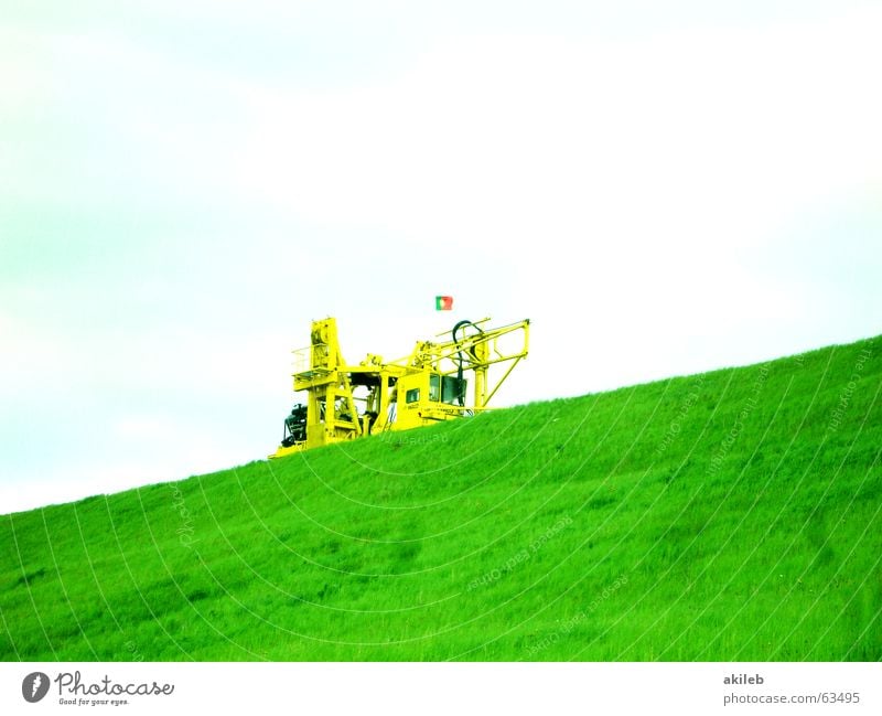 Schieflage Bagger gelb grün Wolken Rasen Himmel diagonal Textfreiraum oben Textfreiraum unten Hügel Damm