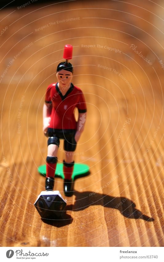 Der Ball hat Ecken... rot schwarz braun Holz weiß Dinge obskur Schatten Sport Tischfußball Spielfigur 1 stoßen Vorderansicht Schwache Tiefenschärfe Maserung