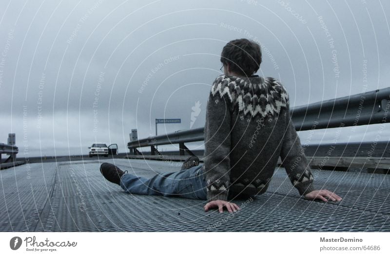 Dann fahrt doch alleine weiter! Mann abstützen Hand Leitplanke grau Wolken Horizont schlechtes Wetter Straßennamenschild Wagen Einsamkeit Ferne Pullover Island