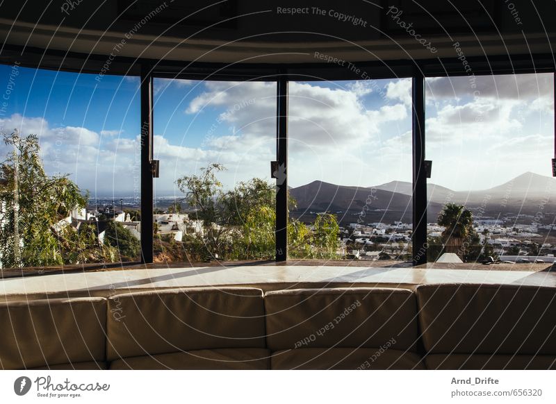 Fensterfront Häusliches Leben Wohnung Traumhaus Innenarchitektur Möbel Sofa Raum Landschaft Himmel Wolken Berge u. Gebirge blau Geborgenheit Warmherzigkeit