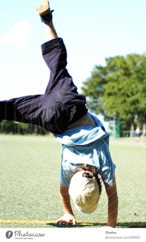 Handständler I Handstand Kind maskulin Artist Turnen Junge Kunstrasen Baum Sträucher Wiese Wolken Sommer heiß Physik Rasen Himmel blau Sonne Wärme Bewegung