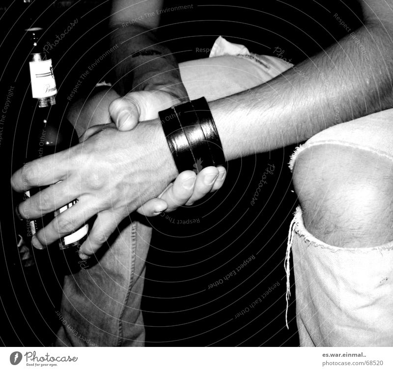 being sexy while drinking beer. Armband Bier schwarz weiß gerissen Knie Licht Hand Finger Fingernagel Gefäße Hose Mann umschließen kaputt lässig Erholung