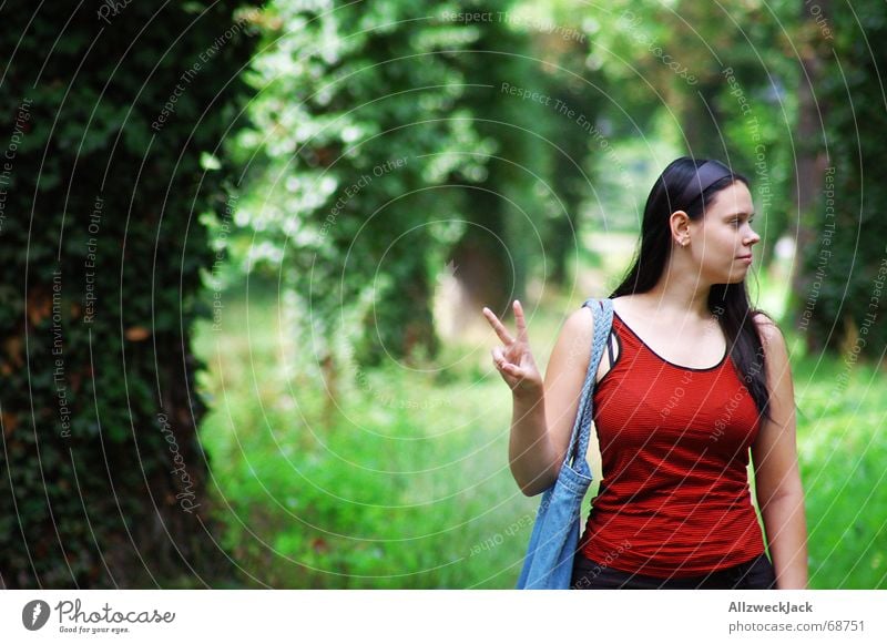 Peace ! Allee grün Frau Fröhlichkeit friedliebend Baum Wald Außenaufnahme Porträt Mensch schaut nach rechts zwei finger rotes shirt Natur peacezeichen