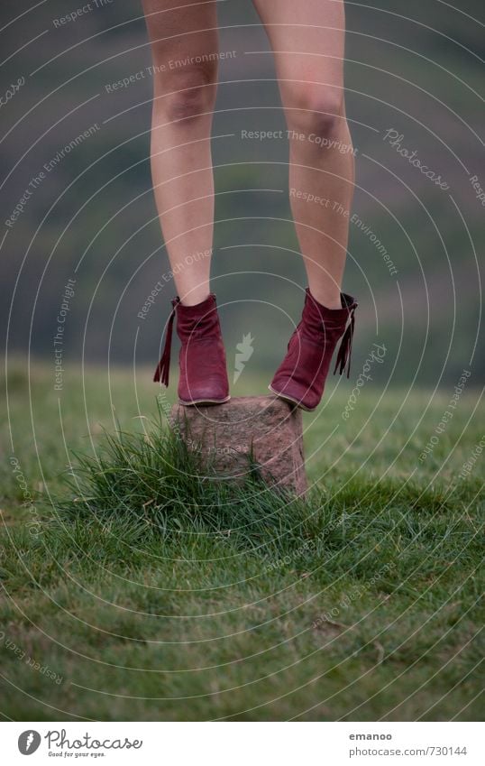 Mädchen mit roten Stiefeln steht auf einem Markierungsstein auf einem grasbewachsenen Hügel Lifestyle elegant Stil schön Ausflug Freiheit Mensch feminin