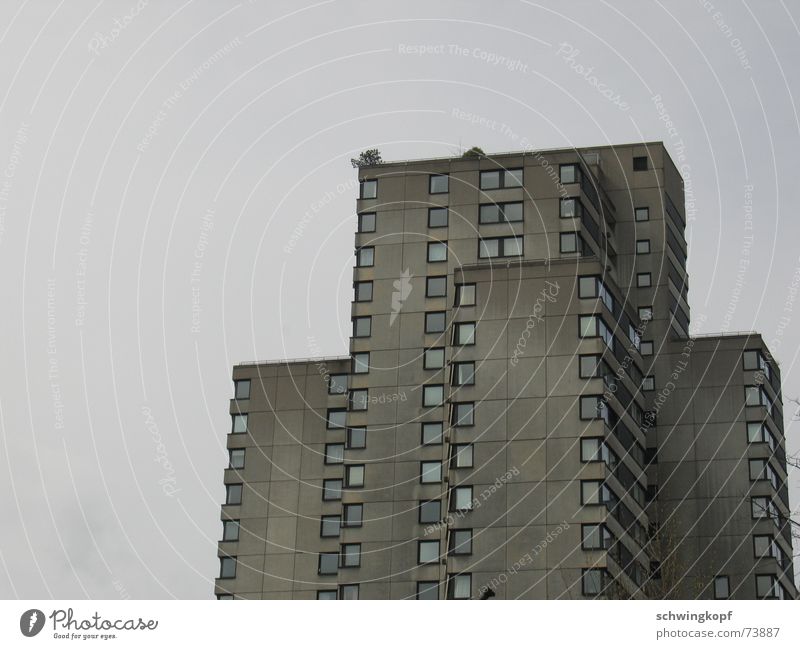 Haus in Grau Hochhaus Fenster Etage grau trist trüb Wohnsiedlung Fassade Balkon Beton Quadrat Wohnung Vorstadt Wetter schäbig Fleck terasse Himmel