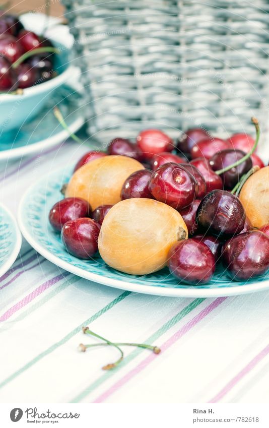 und danach Obst Frucht Ernährung Vegetarische Ernährung Teller frisch lecker gelb rot türkis Lebensfreude genießen Kirsche Mispeln Tischwäsche gestreift Korb