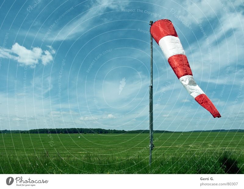 Wind im Sack Windsack Schliere Windrichtung rot Wolken himmelblau gestreift Luft Wiese Flugplatz Gras Fahnenmast hängen grün luftig frisch Wolkenband Luftraum