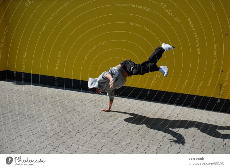 händelbar gelb Lokal Asphalt Wand Parkplatz Sommer Schattenspiel Sport Spielen break Breakdancer Kapuze Tanzen