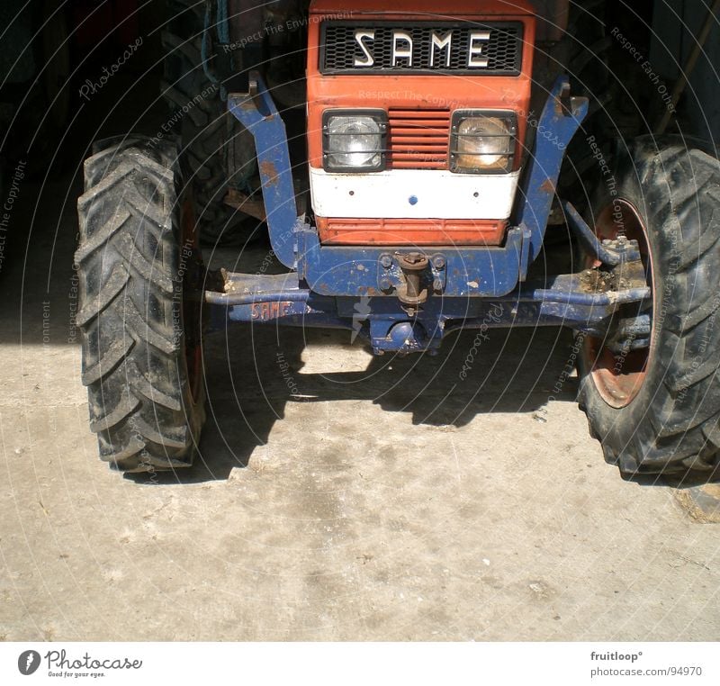 out of the dark Traktor Bauernhof Landwirtschaft blau-rot Verkehr Schatten Rad Sonne Bodenbelag