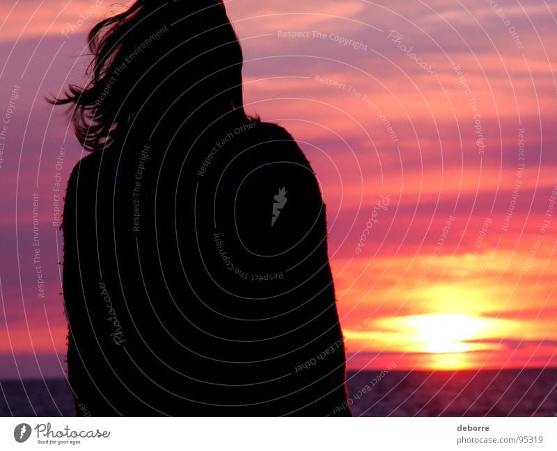 Silhouette einer jungen Frau, die am Strand steht, mit einem rosa Sonnenuntergang im Hintergrund. Romantik rot violett Meer Wolken schwarz Sommer orange Himmel