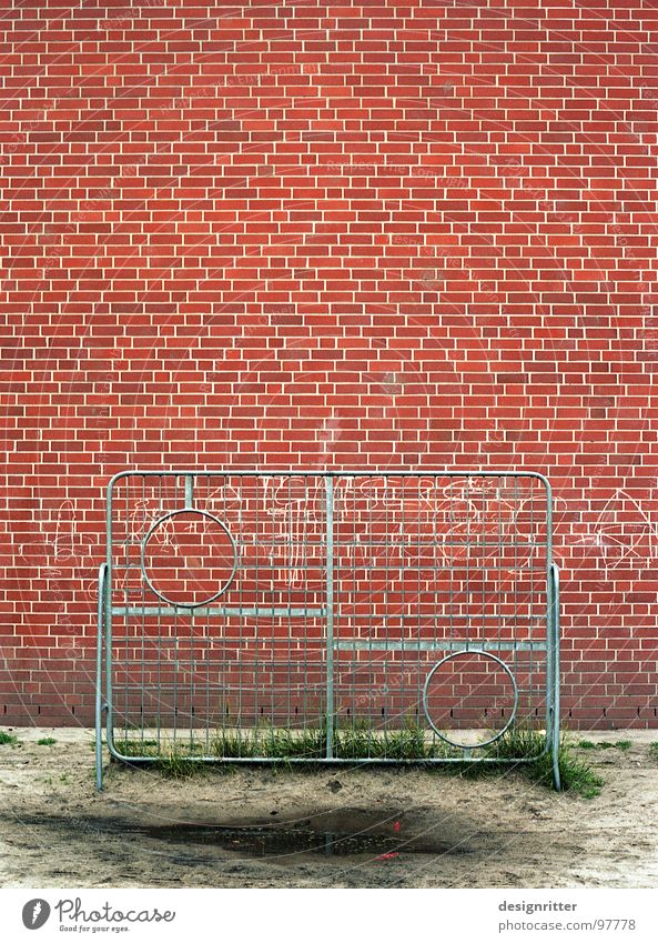 Das runde muss in das runde Gitter Treffer schwierig Mauer Backstein rot Pfütze Ballsport Fußball Schulhof Torwand