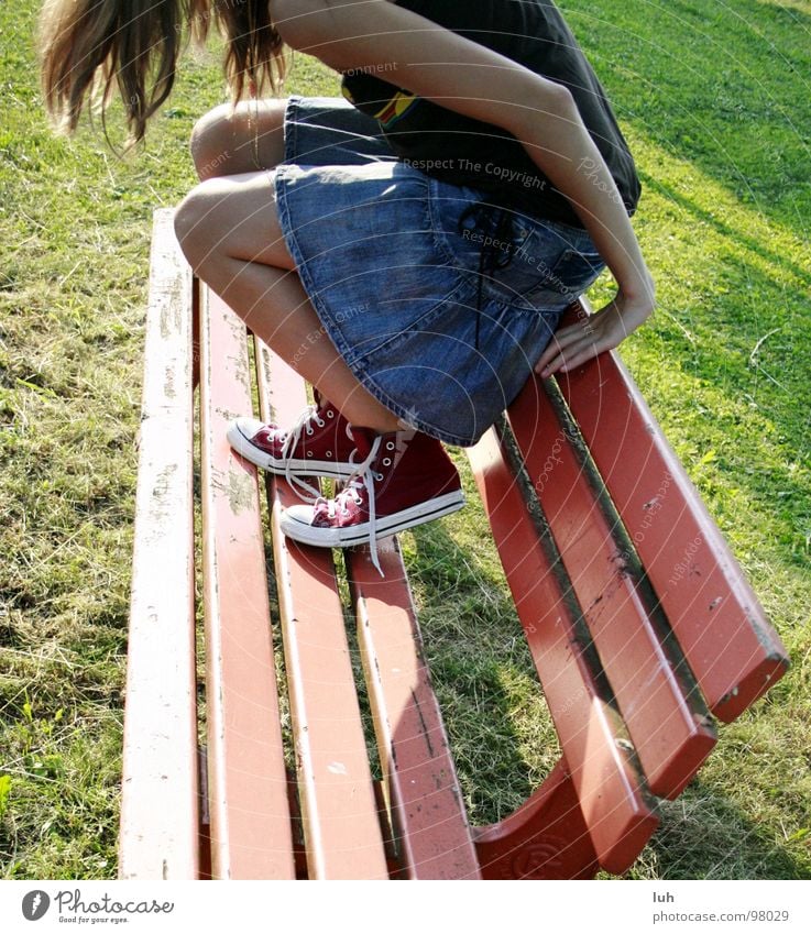 Es liegt etwas in der Luft... rot Jugendliche Chucks Schuhe Suche Sommer springen abstützen geheimnisvoll Bank red Beine sitzen sit down umgucken Amerika Rasen