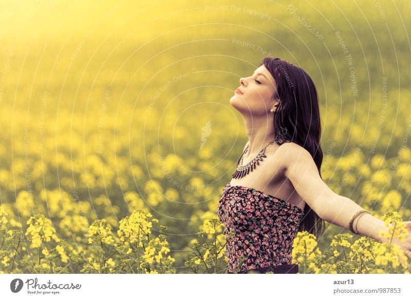 Wunderschöne junge Frau im Sommer in einem Meer aus gelbem Raps bis zum Horizont. Hübsches Mädchen mit Lebensfreude geniesst die Sonnenschein Pause und das Leben. Erholung und Energie tanken vom Zeit Umwelt Stress in der Natur Idylle.