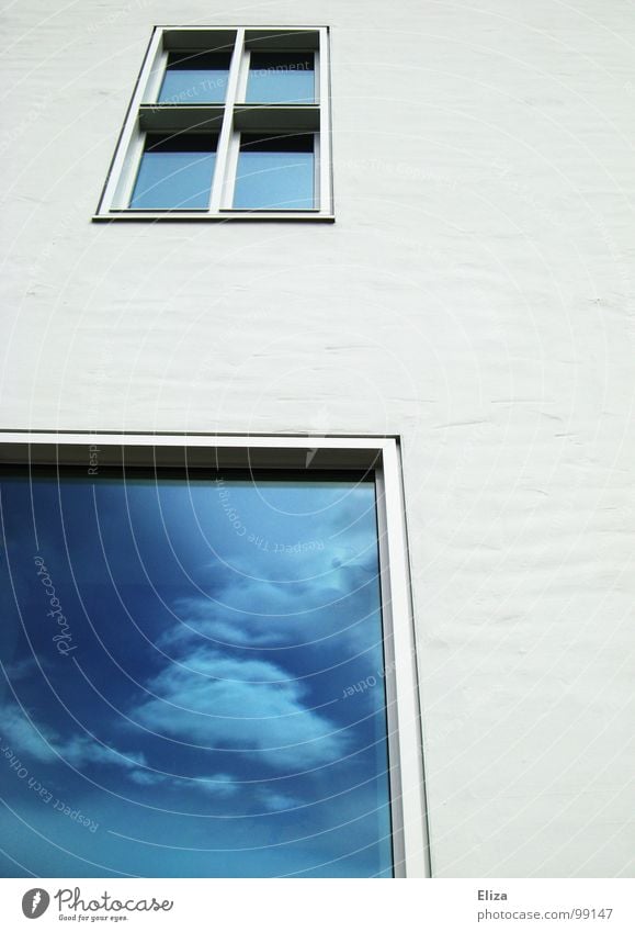 Eine weiße Hauswand mit Fenstern in denen sich blauer Himmel mit Wolken spiegelt Spiegelung Fassade Ausblick Zukunft Architektur Reflexion & Spiegelung Gebäude