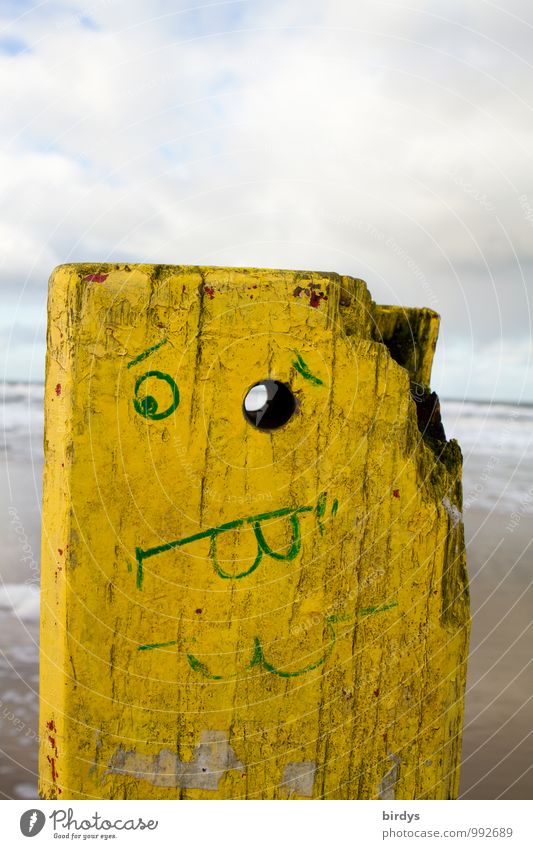 Vollpfosten Wolken Strand Holz Blick außergewöhnlich lustig gelb Kreativität skurril Gesichtsbemalung Humor Holzkopf Pfosten Auge Gesichtsausdruck Farbfoto