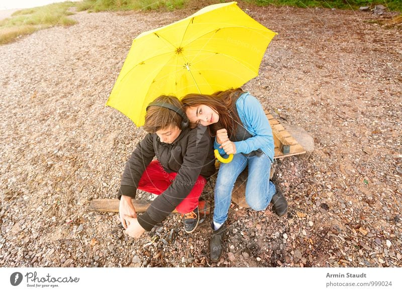 Geschwisterpaar unter einem gelben Regenschirm am Strand Lifestyle Erholung Ausflug Mensch maskulin feminin Paar Jugendliche 2 13-18 Jahre Kind Umwelt Erde