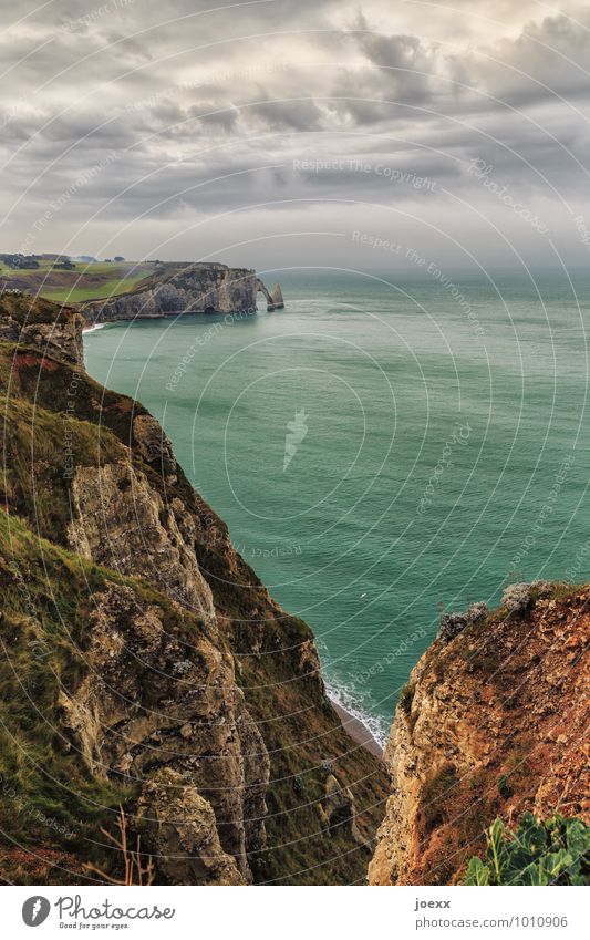 Étretat Nature Landscape Sky Clouds Horizon Bad weather Rock Mountain Waves Coast Ocean Large Tall Brown Gray Green Tourism Environment Arch Colour photo