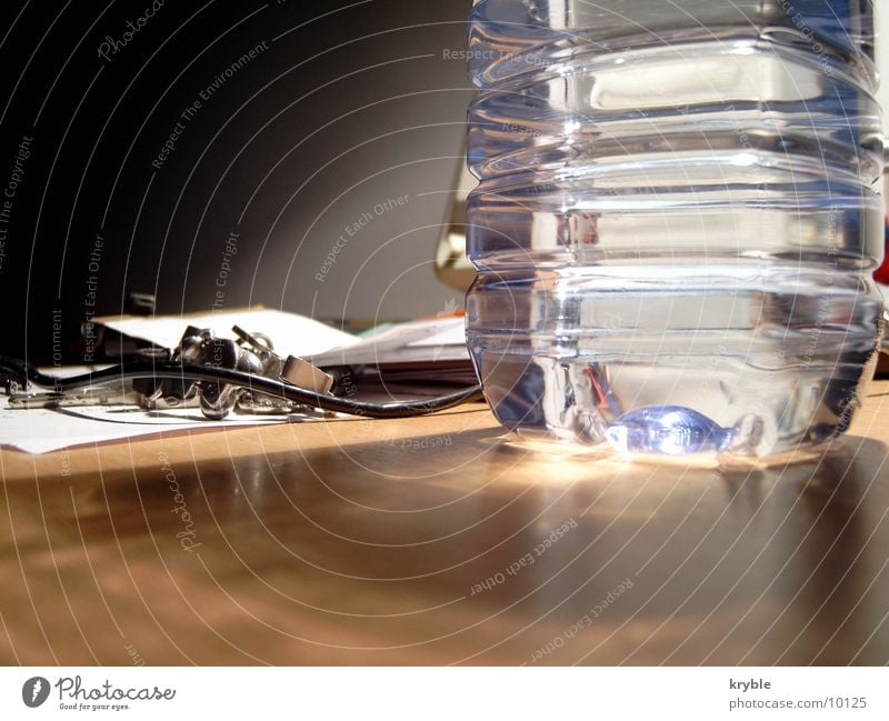 water bottle Bottle of water Bottle of mineral water Table Trash Light Glittering Water volvic Desk mushy Lamp reflection Smoothness Shadow shadow incidence