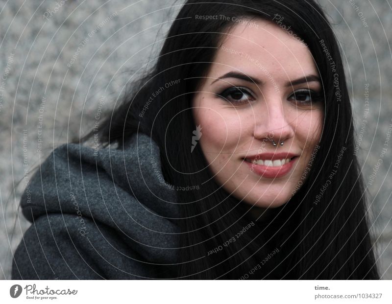 smiling woman Feminine 1 Human being Wall (barrier) Wall (building) Coat Piercing Black-haired Long-haired Observe Smiling Laughter Looking Wait Elegant pretty