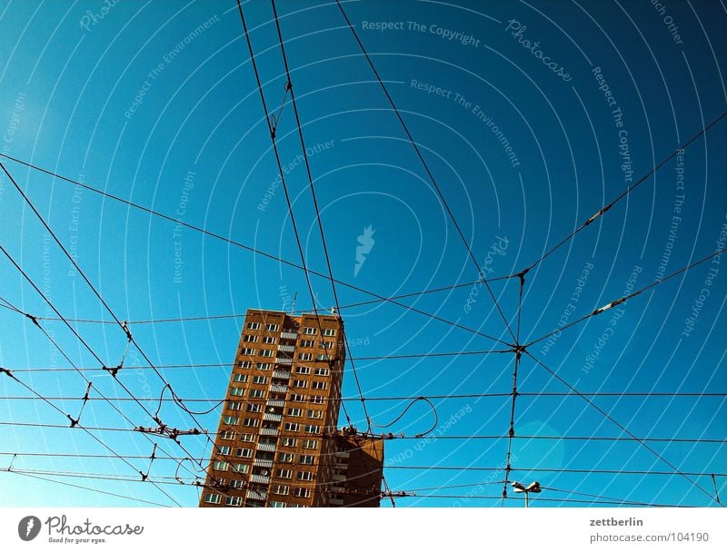 catenary wire Overhead line Tram Public transit Electricity House (Residential Structure) High-rise Story Window Facade Sky blue Muddled Chaos Architecture